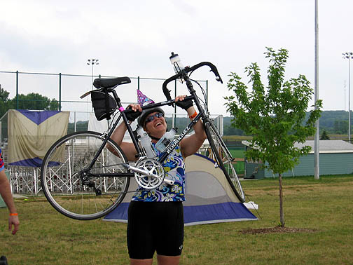 Excited at finishing, a rider lifts her Rodriguez over her head